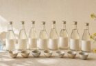 生成り色の空間に8本の日本酒と酒器を並べた飲み比べイメージ