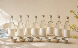 生成り色の空間に8本の日本酒と酒器を並べた飲み比べイメージ
